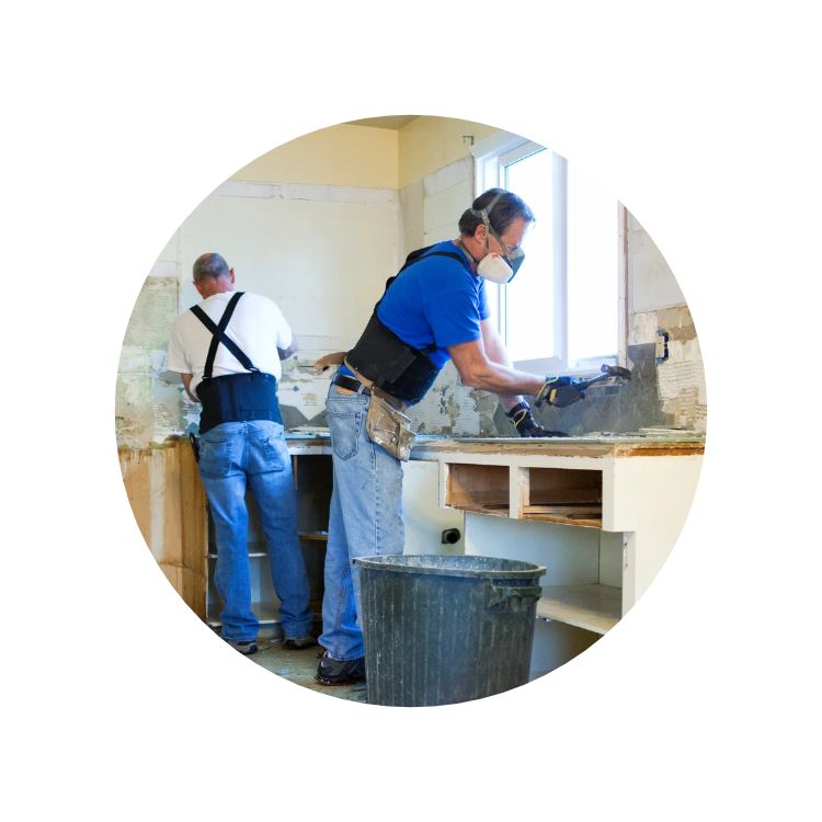 Two middle aged men wearing back braces and dust masks, doing a kitchen renovation
