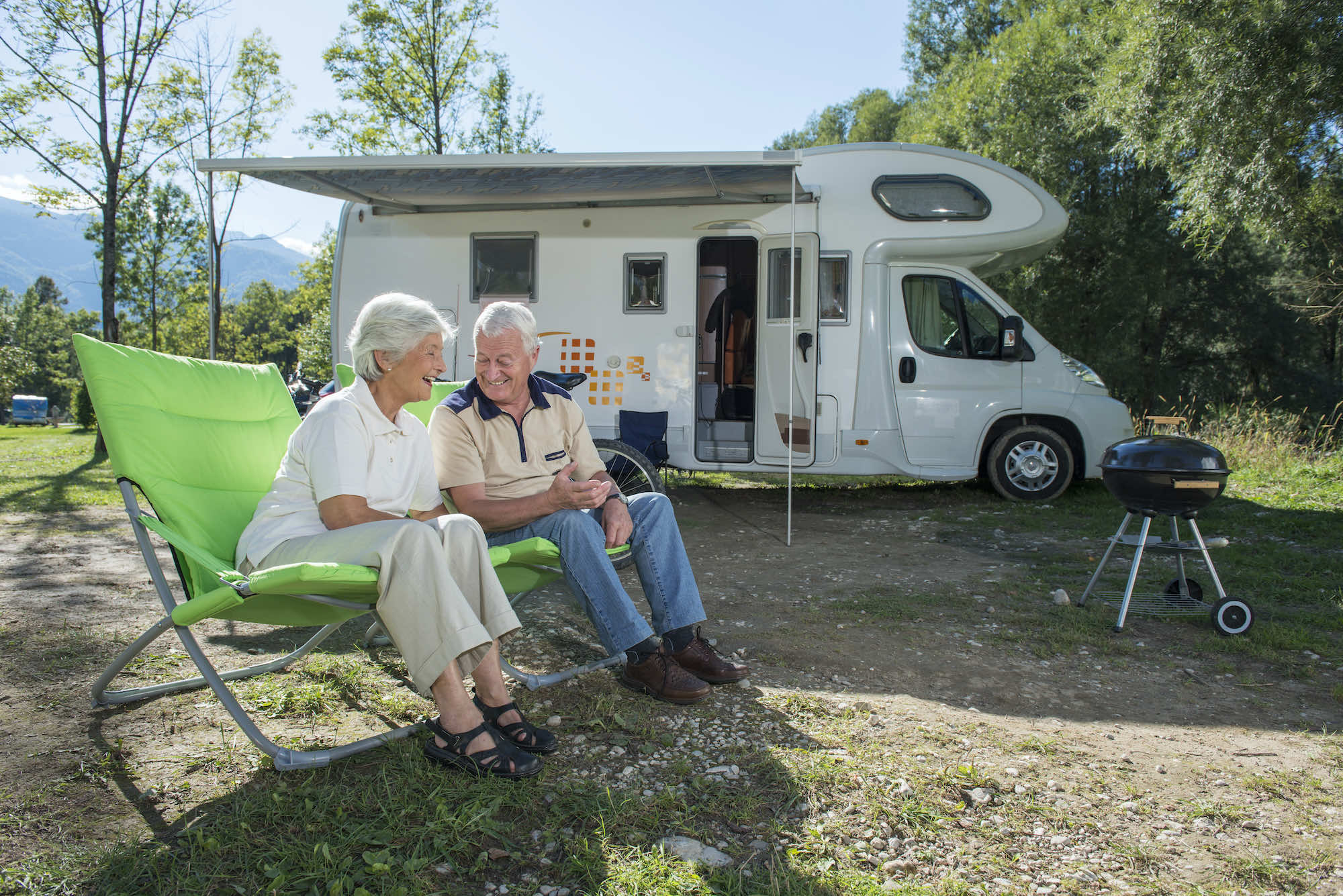 Older couple in camp chairs near RV